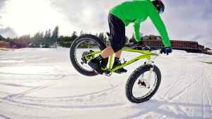 On a fatbike this man is making a nose wheelie in the snow