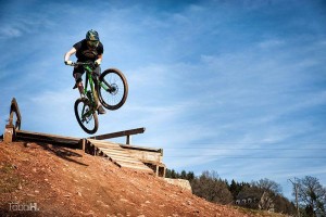 A downhill mountainbiker is performing a jump in bike park Malmedy