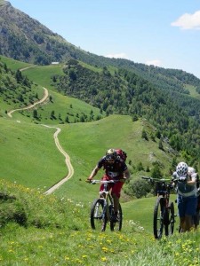 two mountainbikers are climbing to the top for a great downhill. One is still riding the others had to walk
