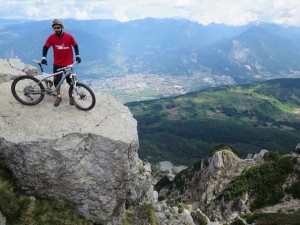 With is trail-addicts shirt standing on a big rock with a beautiful view over the valley