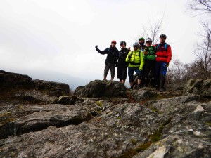 6 mountainbikers staan op de top van de berg. het weer is grijs en regenachtig