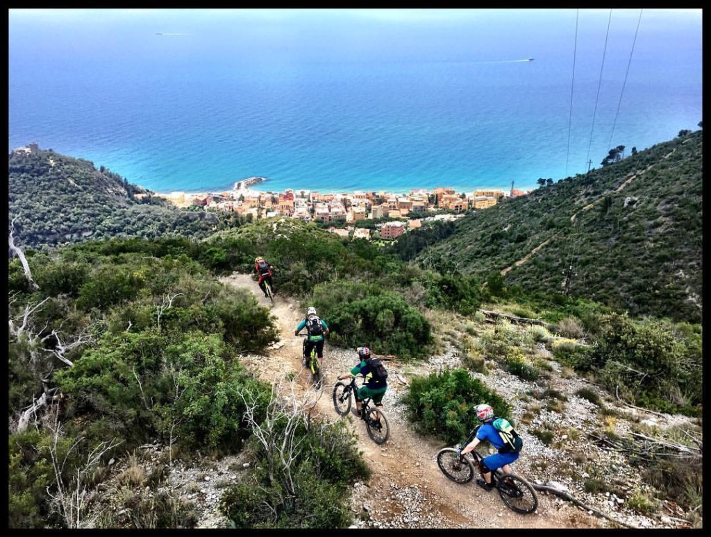 IN een treintje rijden de mountainbikers over een trail. Het uitzicht is op de prachtige azuur blauwe zee bij finale ligure