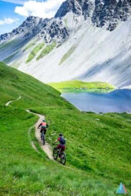 2 mountainbikers rijden over de trail door het groene gras